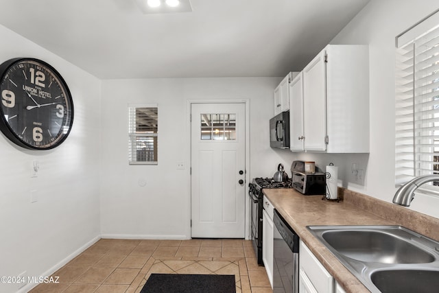 kitchen featuring light tile patterned floors, white cabinetry, stainless steel dishwasher, and sink