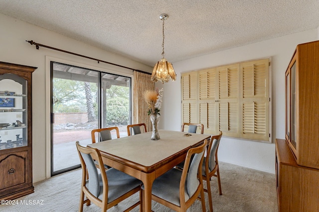 carpeted dining area with a notable chandelier and a textured ceiling