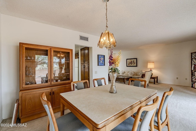 dining room featuring light colored carpet, a textured ceiling, and a chandelier