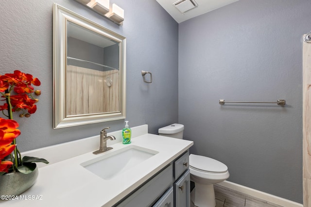 bathroom featuring vanity, toilet, and a shower