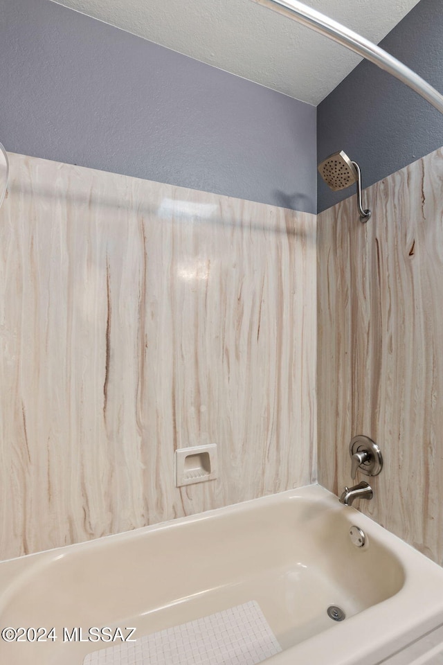 bathroom with a textured ceiling and bathing tub / shower combination