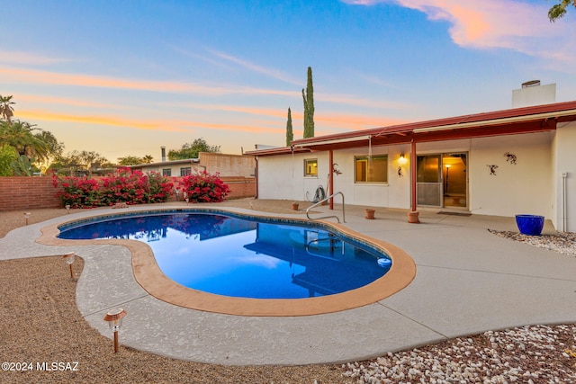 pool at dusk featuring a patio