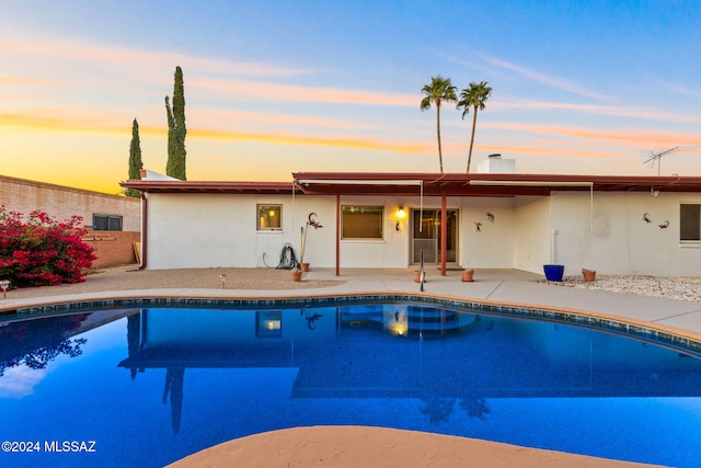 pool at dusk with a patio area