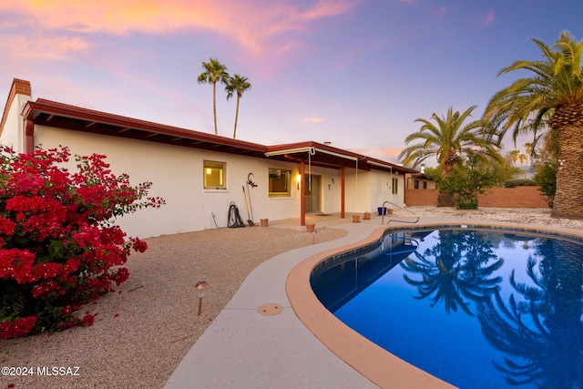 pool at dusk featuring a patio