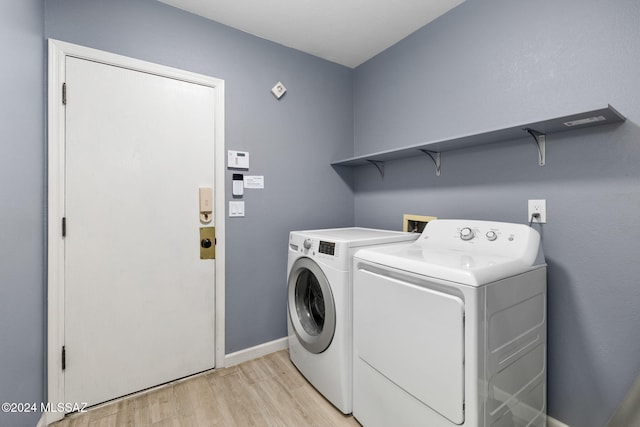 clothes washing area with light wood-type flooring and washer and clothes dryer