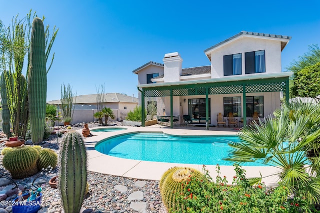 rear view of house featuring a hot tub, a fenced in pool, fence, a patio area, and stucco siding