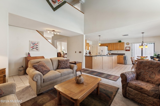 living area with a chandelier, a high ceiling, light tile patterned flooring, and visible vents