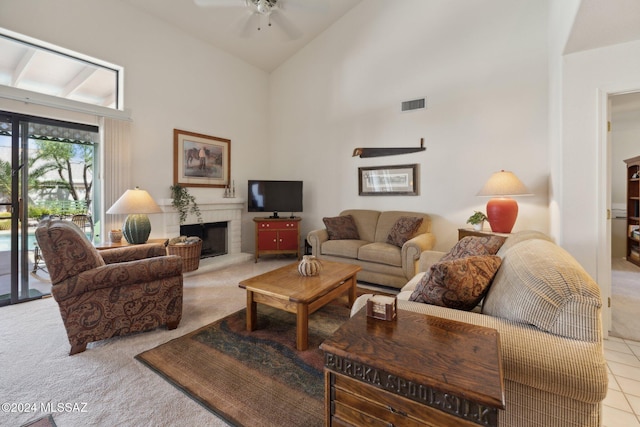 carpeted living room featuring a fireplace with raised hearth, high vaulted ceiling, ceiling fan, and visible vents