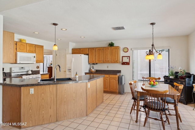 kitchen featuring white appliances, visible vents, dark countertops, a peninsula, and a sink