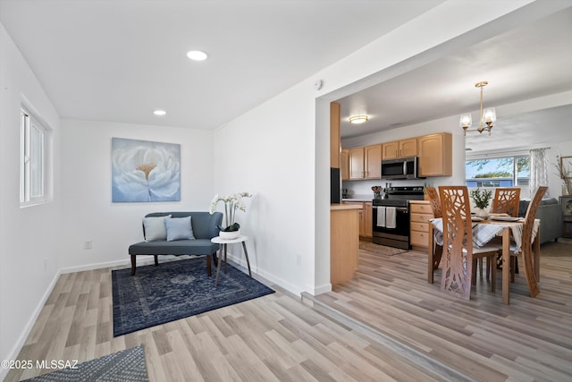 interior space featuring an inviting chandelier, light wood-type flooring, light brown cabinets, pendant lighting, and stainless steel appliances