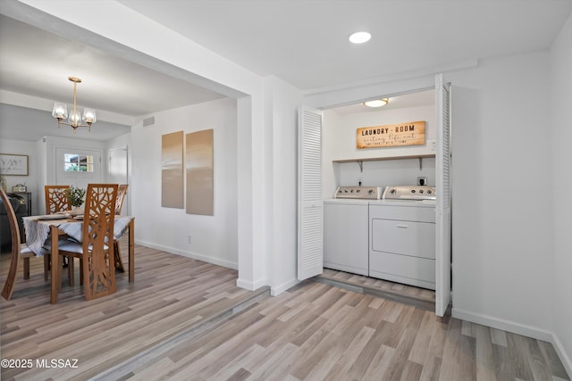 dining area featuring light wood-type flooring, washer and dryer, and a notable chandelier