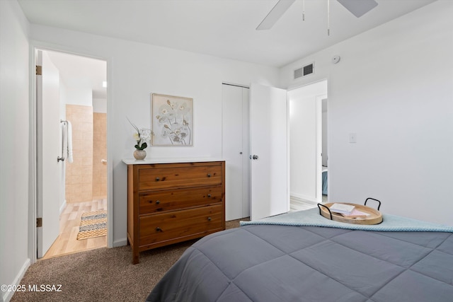 carpeted bedroom featuring ceiling fan, ensuite bath, and a closet