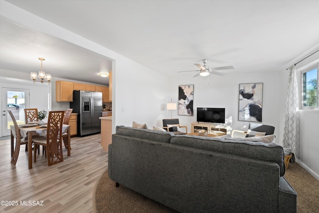 living room with ceiling fan with notable chandelier and light hardwood / wood-style flooring