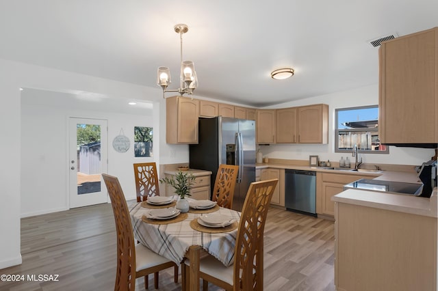 dining area featuring sink, a chandelier, and light wood-type flooring