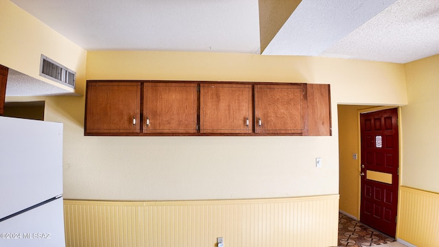 kitchen featuring radiator, white fridge, and a textured ceiling