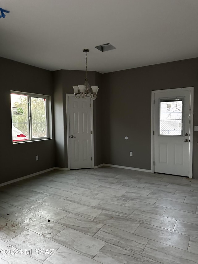 unfurnished dining area featuring plenty of natural light and a chandelier