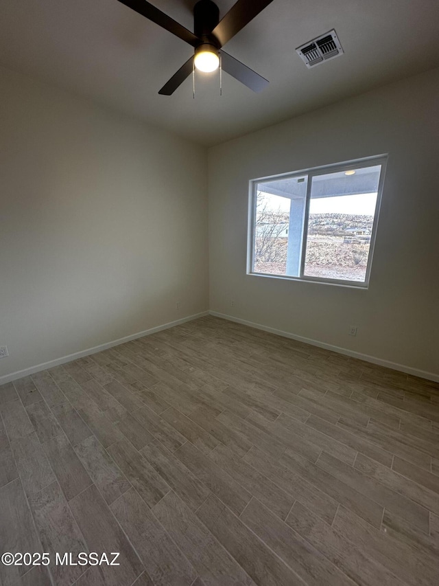 spare room featuring a ceiling fan, wood finished floors, visible vents, and baseboards