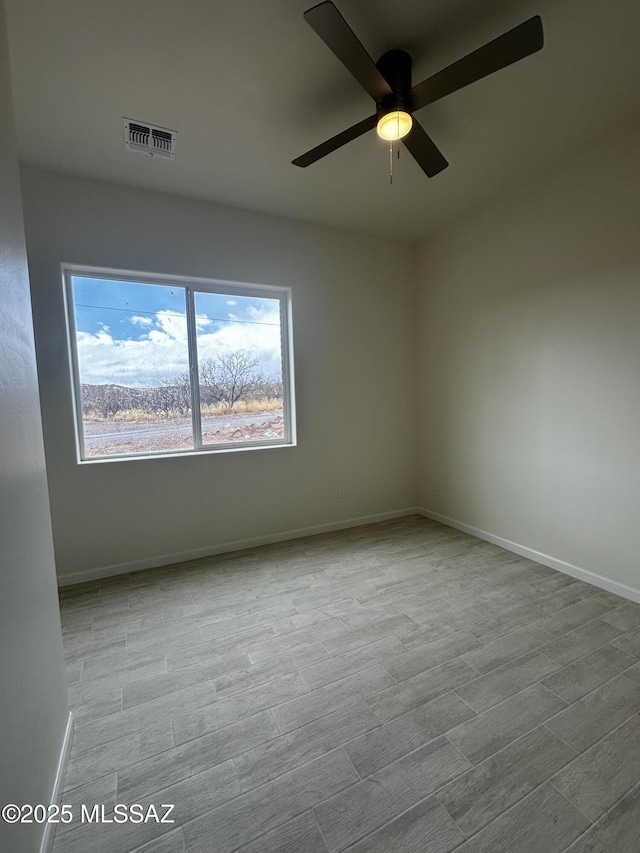 empty room featuring ceiling fan, wood finished floors, visible vents, and baseboards