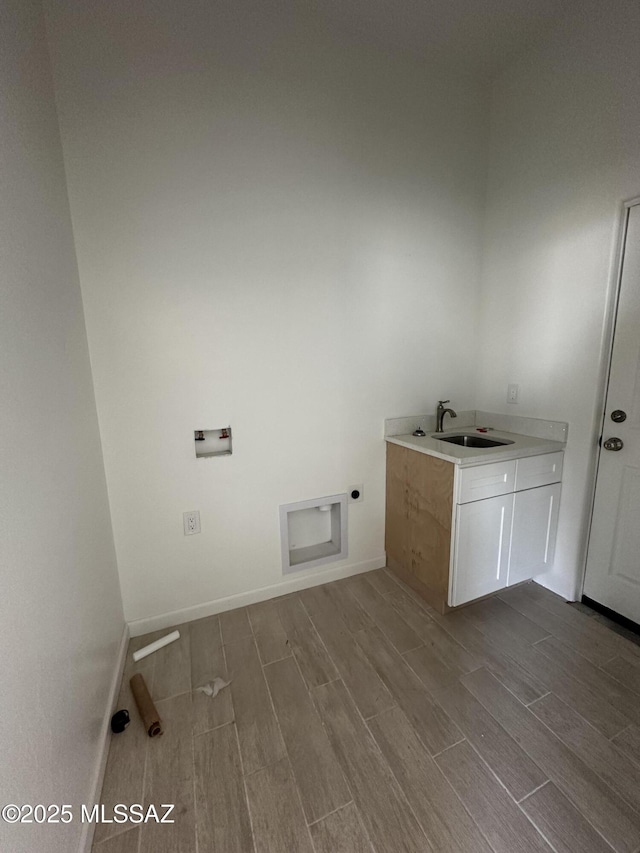 clothes washing area with hookup for a washing machine, hookup for an electric dryer, wood tiled floor, cabinet space, and a sink