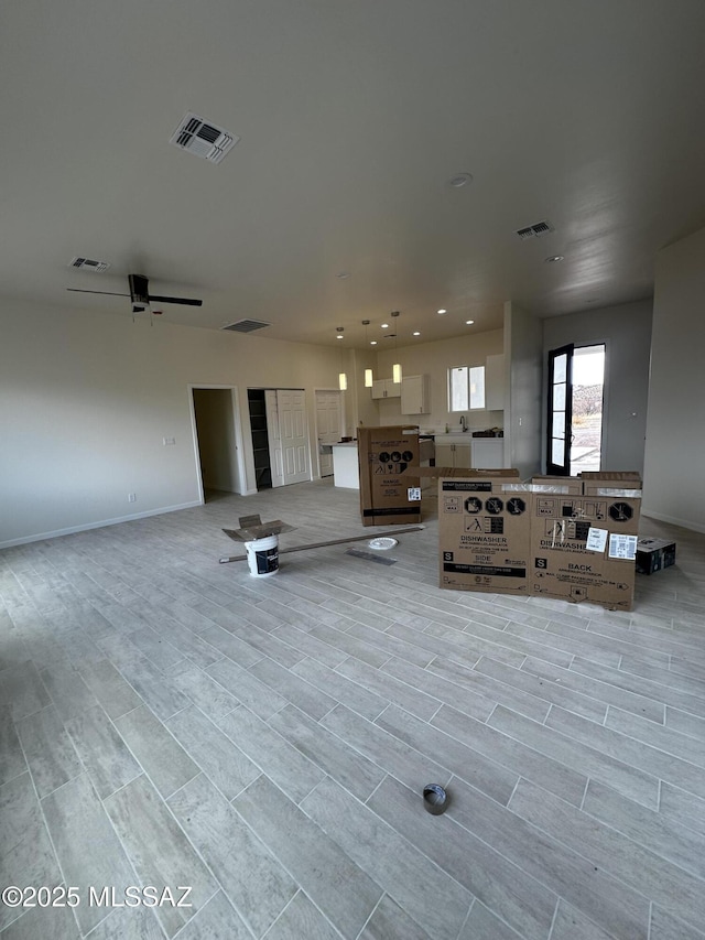 unfurnished living room with light wood-style floors, baseboards, and visible vents