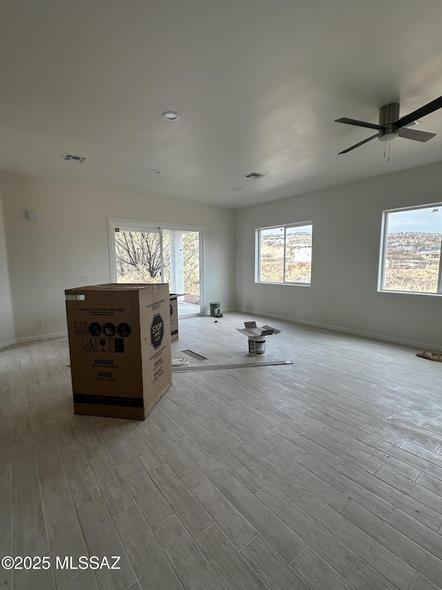 unfurnished living room featuring visible vents, baseboards, a ceiling fan, and light wood finished floors