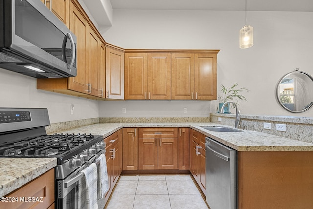 kitchen featuring light stone counters, light tile patterned flooring, stainless steel appliances, decorative light fixtures, and sink