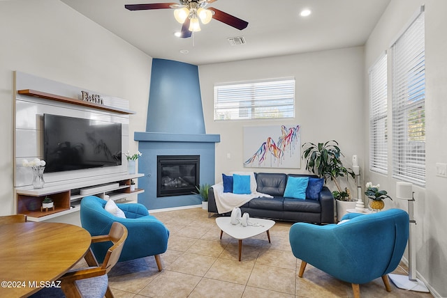 tiled living room featuring a fireplace and ceiling fan