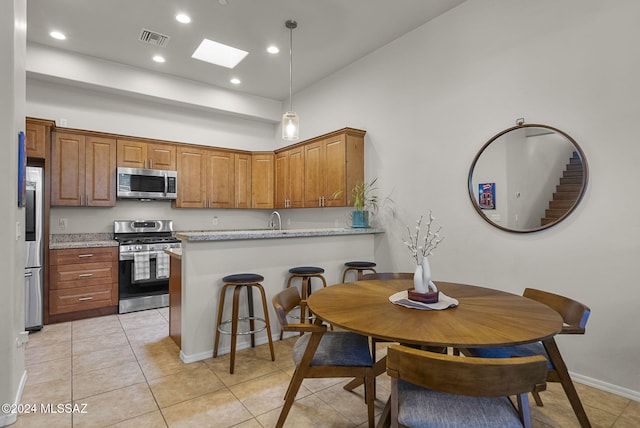 kitchen featuring light stone countertops, kitchen peninsula, light tile patterned flooring, and stainless steel appliances
