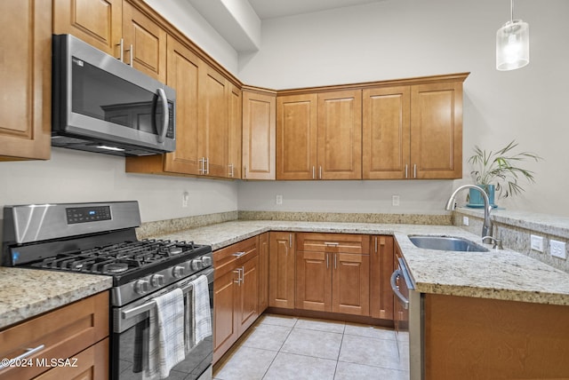 kitchen with light stone countertops, appliances with stainless steel finishes, sink, and light tile patterned floors