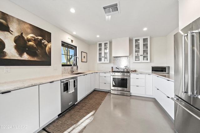 kitchen featuring backsplash, white cabinets, sink, appliances with stainless steel finishes, and custom range hood