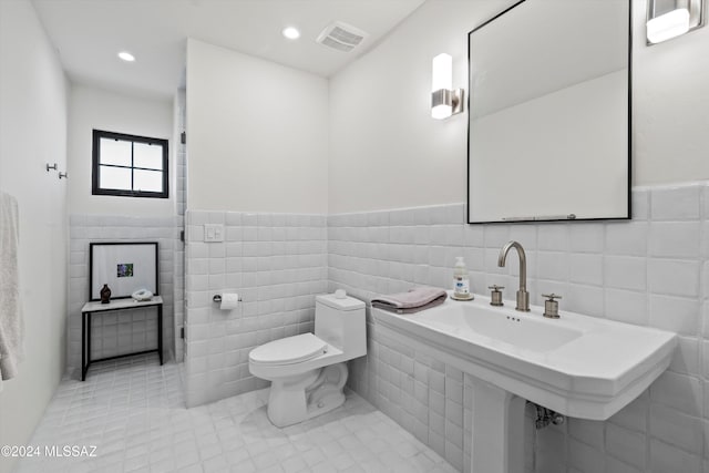 bathroom with tile patterned flooring, sink, toilet, and tile walls