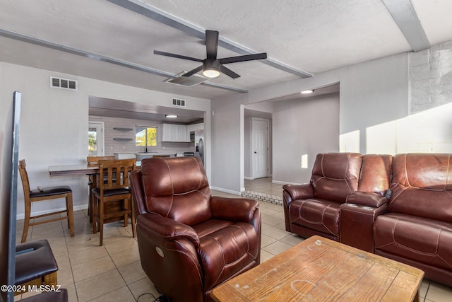 tiled living room with ceiling fan and a textured ceiling