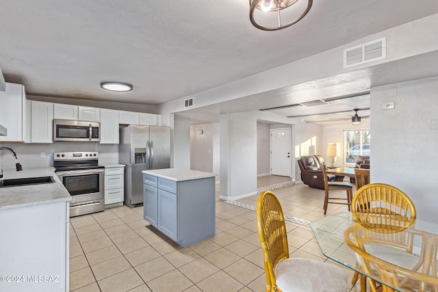 kitchen featuring a center island, white cabinets, sink, light tile patterned floors, and appliances with stainless steel finishes