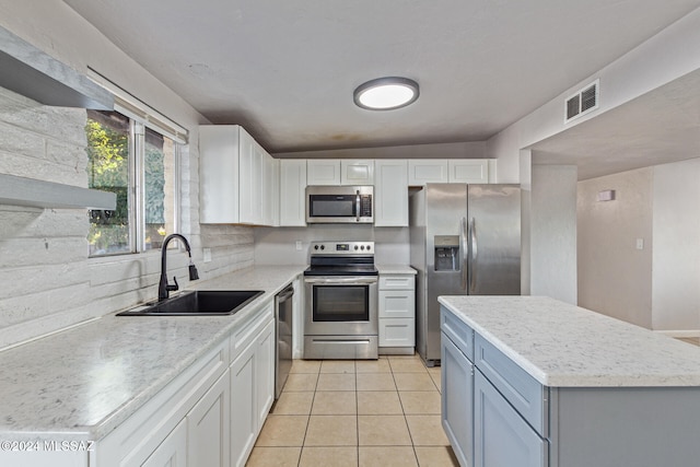 kitchen featuring light tile patterned flooring, sink, appliances with stainless steel finishes, a kitchen island, and white cabinetry