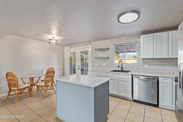 kitchen featuring white cabinetry, sink, stainless steel dishwasher, backsplash, and a kitchen island