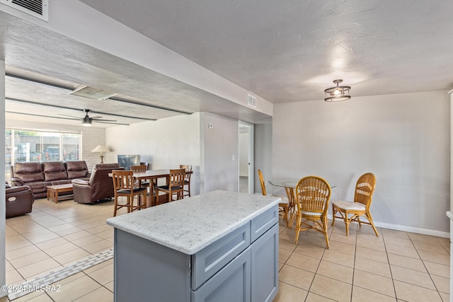 kitchen with light tile patterned floors, a center island, and ceiling fan