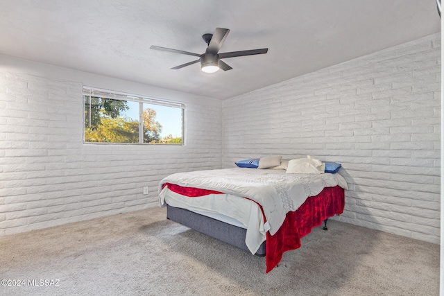 carpeted bedroom with ceiling fan and brick wall