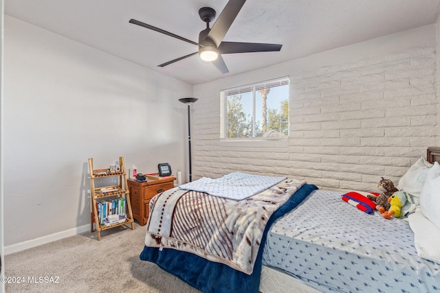 bedroom featuring ceiling fan, light carpet, and brick wall