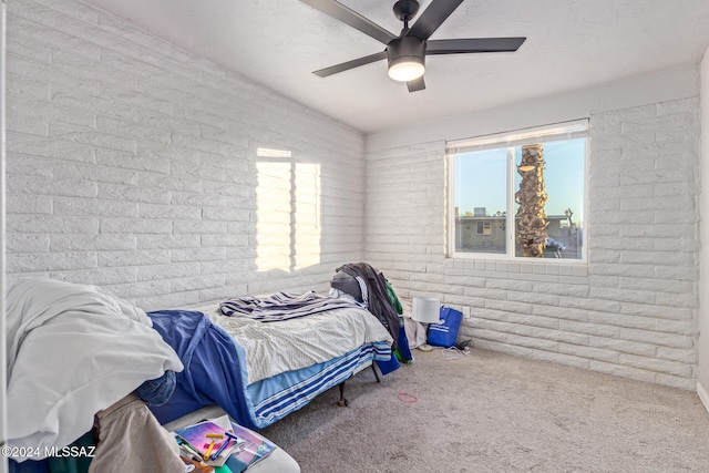 carpeted bedroom featuring ceiling fan and brick wall