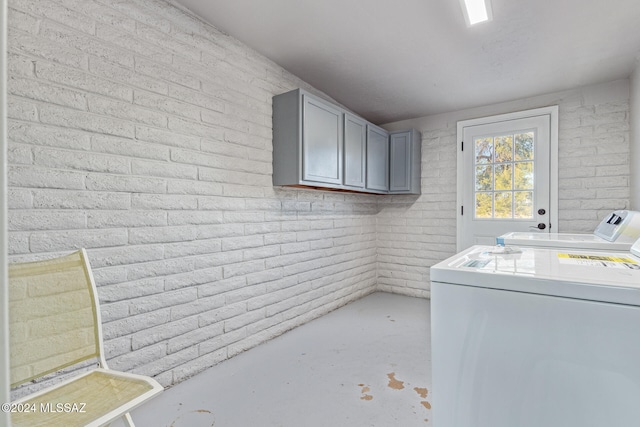 washroom with separate washer and dryer, cabinets, and brick wall