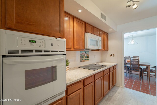 kitchen with decorative backsplash, light tile patterned floors, light stone countertops, pendant lighting, and white appliances