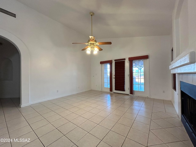 unfurnished living room with ceiling fan, light tile patterned floors, and high vaulted ceiling