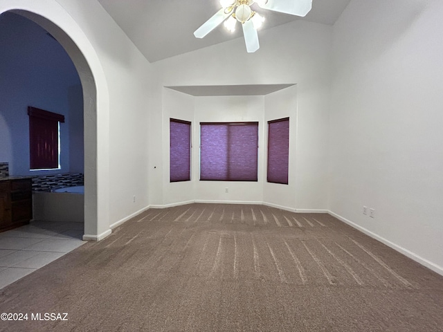 carpeted empty room featuring high vaulted ceiling and ceiling fan