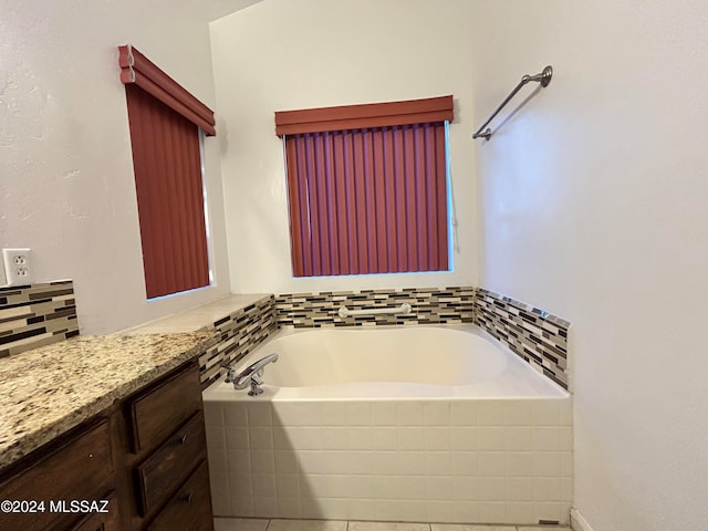 bathroom featuring tile patterned flooring, vanity, and a relaxing tiled tub