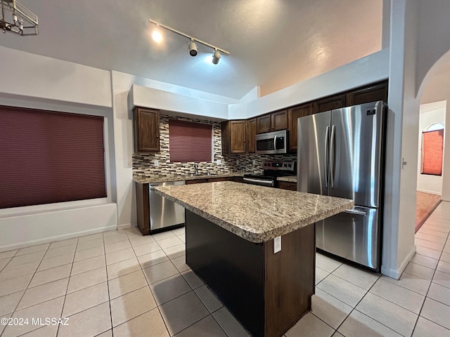 kitchen featuring a center island, backsplash, light tile patterned floors, dark brown cabinetry, and stainless steel appliances