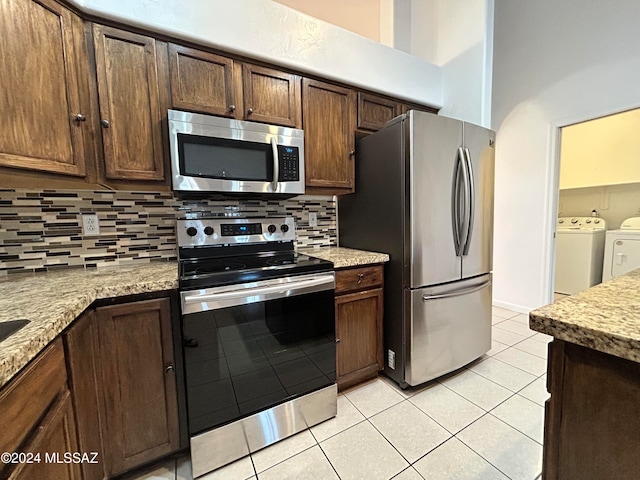 kitchen with backsplash, separate washer and dryer, light tile patterned flooring, light stone counters, and stainless steel appliances