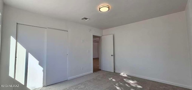 unfurnished bedroom with a closet and light colored carpet