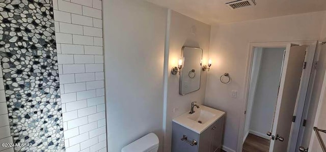 bathroom with toilet, vanity, and wood-type flooring