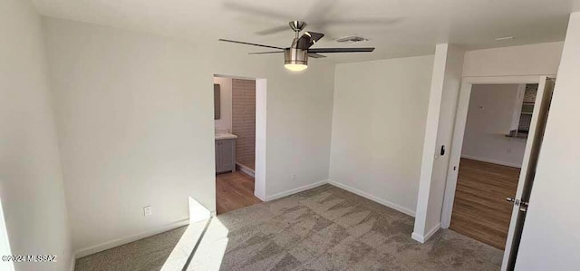 interior space with light colored carpet, ceiling fan, and ensuite bath