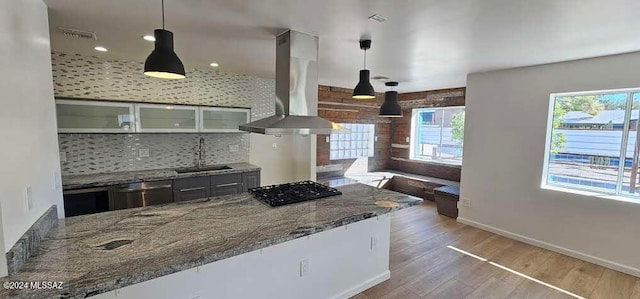 kitchen with sink, decorative light fixtures, dishwasher, wall chimney range hood, and decorative backsplash